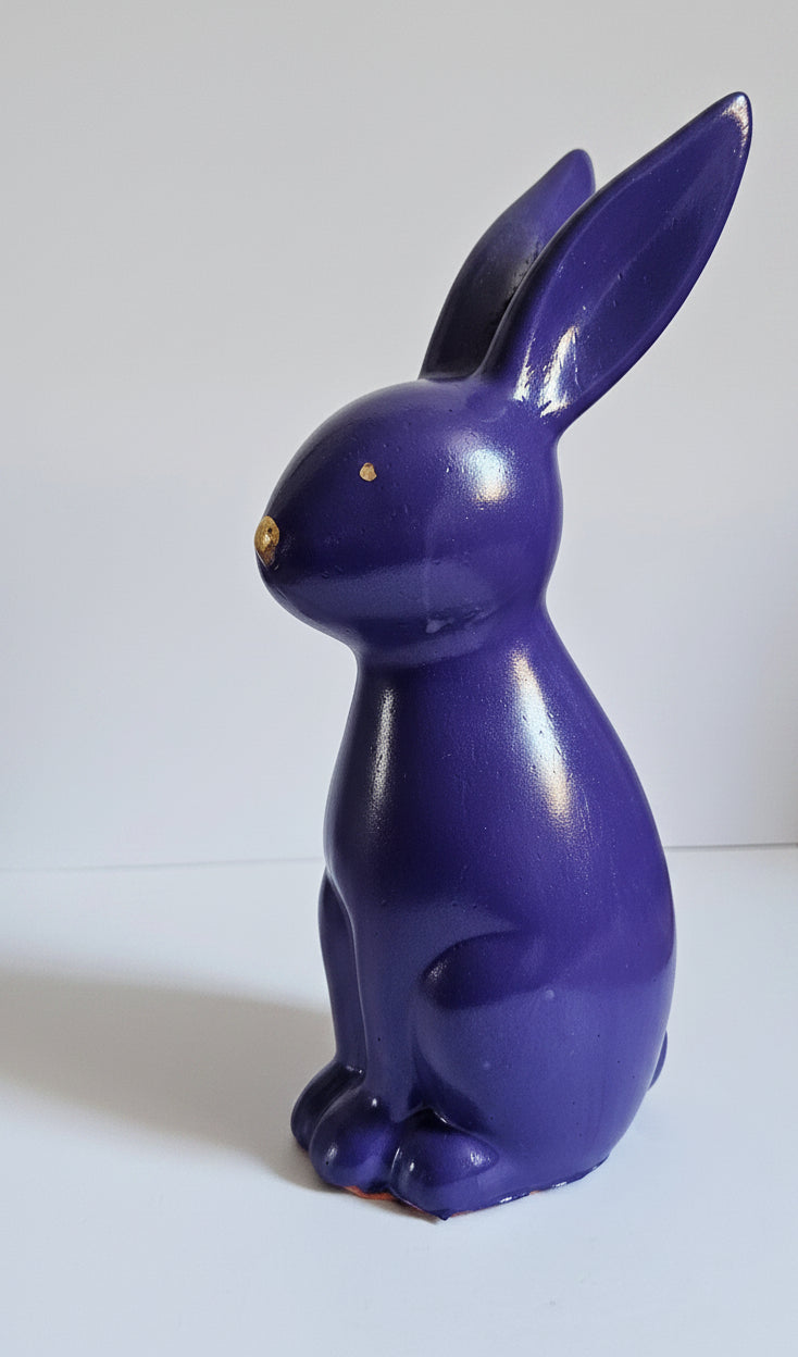 A glossy, deep purple ceramic rabbit figurine with small gold-colored eyes, shown against a plain white background.